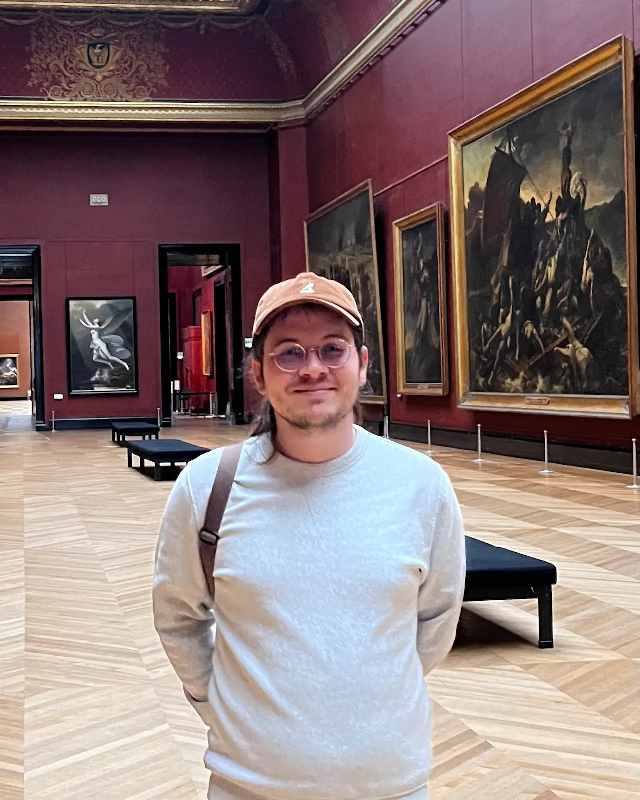Simon Gaulier in a gallery at the Louvre, in front of 19th-century French paintings.
